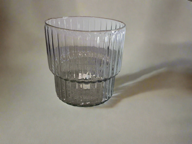 Clear glass ribbed vase with a pedestal on a textured background