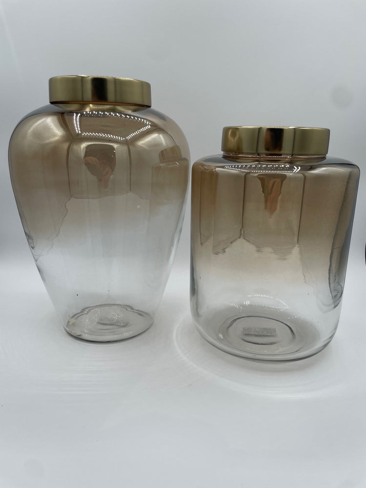 Two beige ombre glass vases with gold caps on a white background