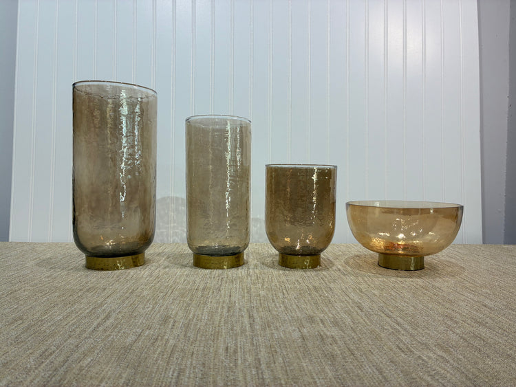 Set of four beige glass vases on a textured surface with a neutral background