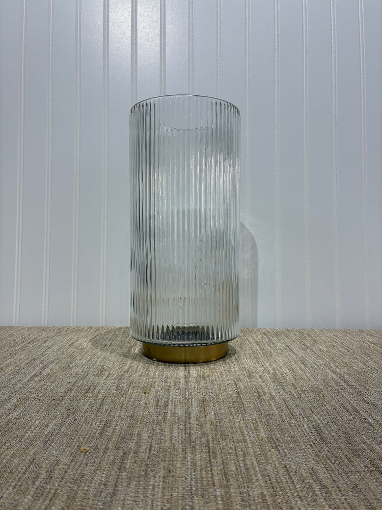 Clear glass ribbed  cylindrical vaseon a textured surface