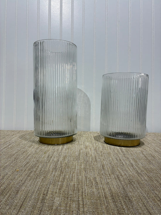 Two ribbed clear glass vase or  candle holders on a textured surface