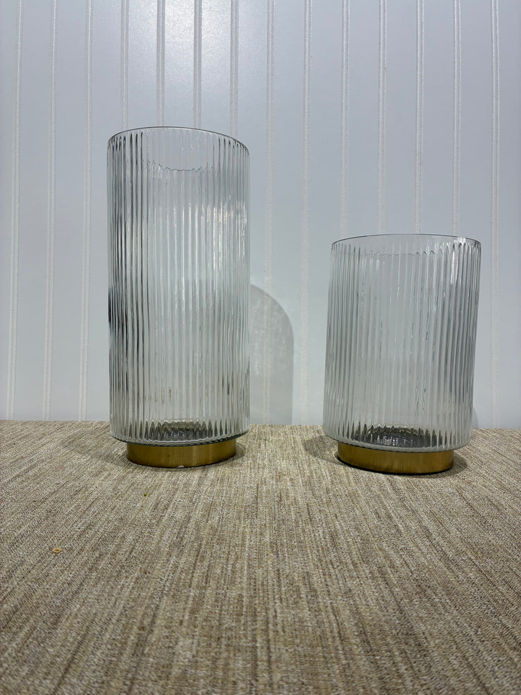 Two ribbed clear glass vase or  candle holders on a textured surface