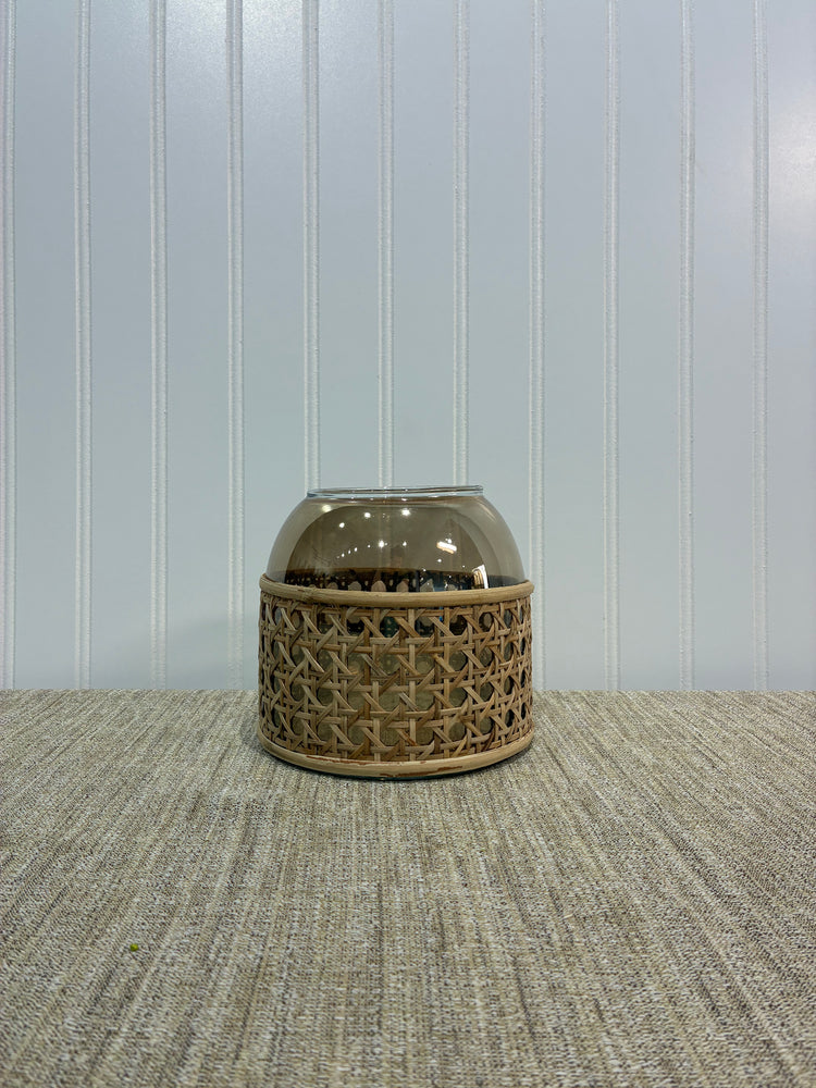 Decorative beige glass vase with woven design on a textured surface