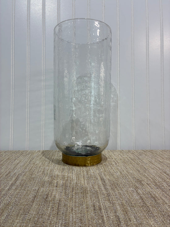 large Clear glass vase with a gold cap on a textured surface