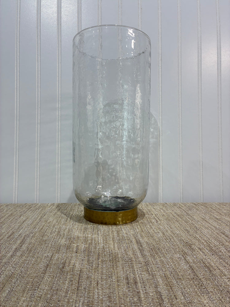 large Clear glass vase with a gold cap on a textured surface
