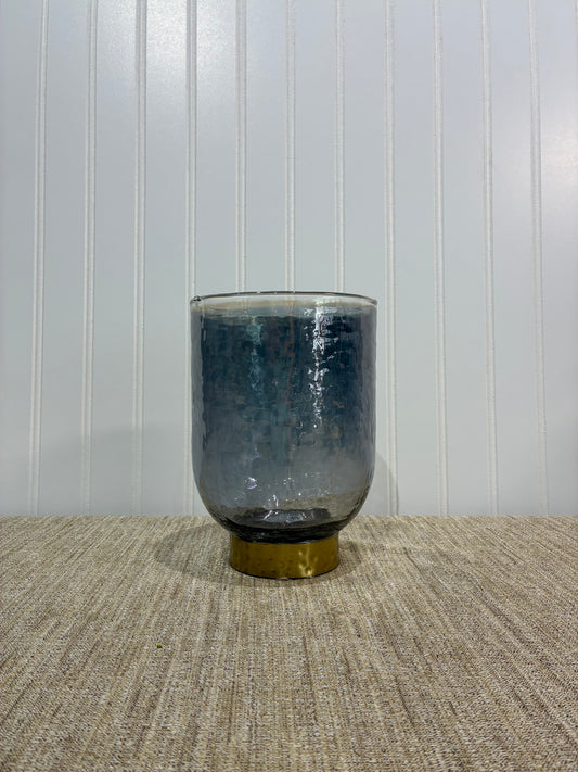 Smoky cylindrical vase with gold ring on a textured surface with a white background