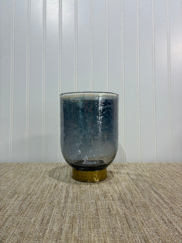 Smoky cylindrical vase with gold ring on a textured surface with a white background