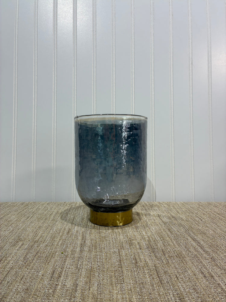 Smoky cylindrical vase with gold ring on a textured surface with a white background