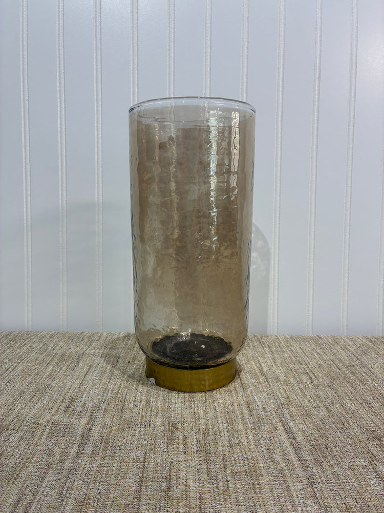 Beige glass Vase with a gold ring pedastal on a textured surface