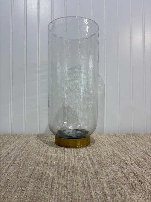 large Clear glass vase with a gold cap on a textured surface