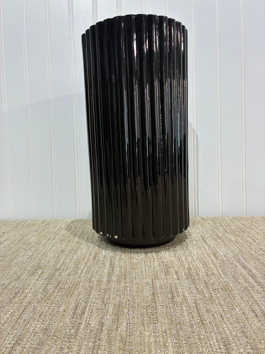 Tall Black cylindrical vase on a textured surface with a white background