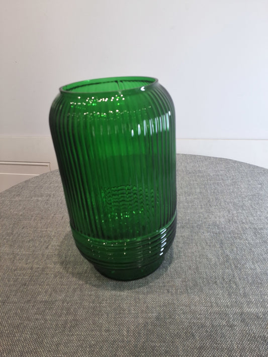 Green ribbed vase on a gray surface with white background